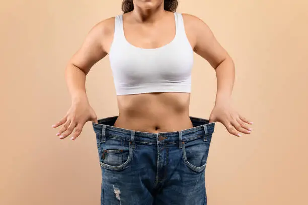 Woman showing weight loss in oversized jeans