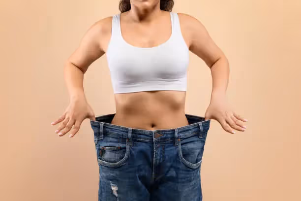 Woman showing weight loss in oversized jeans