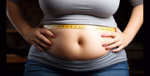 Una mujer midiendo su cintura con una cinta métrica, destacando su sección media y con las manos en las caderas, simbolizando esfuerzos de pérdida de peso o fitness.