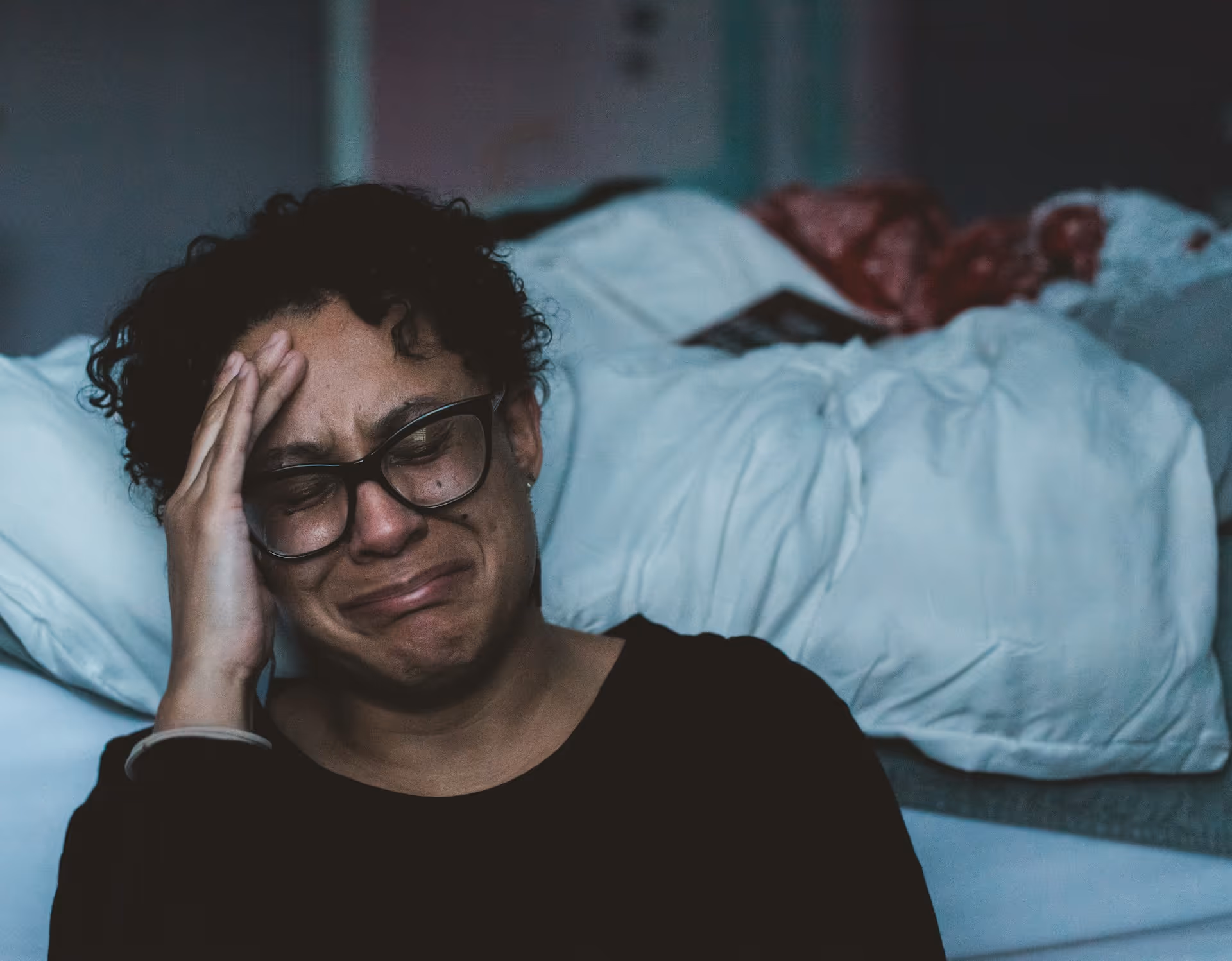 A woman crying beside a bed